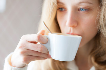  Young woman drinking coffee. Cup of hot beverage