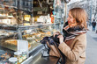 © EdNurg - Street portrait of smiling beautiful young woman buying fast food snacks at stall in europe