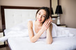 © F8  \ Suport Ukraine - Woman lying at the end of the bed underneath the quilt and smiling, with her head resting upon her hand with the other in her hair.