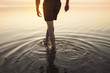 © Astrakan Images - Man in shorts wading in sea at sunset