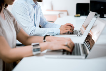 Working people in office, typing on laptop keyboard