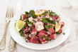 octopus salad with lemon on white dish on wooden background
