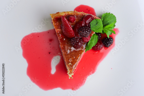 Fotografija Top view of cheesecake with cherry, strawberry and dewberry decorated with syrup
