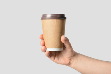 Wall Mural - Mockup of male hand  holding a Coffee paper cup isolated on light grey background.