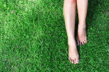 Woman Legs Relax Feeling On Green Grass Background With Light Of Sun