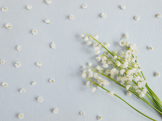 Wall Mural - Lily of the valley on a blue paper textured background. Pattern of small flowers of the may-lily. Abstract floral background.