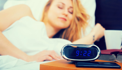 Wall Mural - woman sleeping near clock and book in bedroom