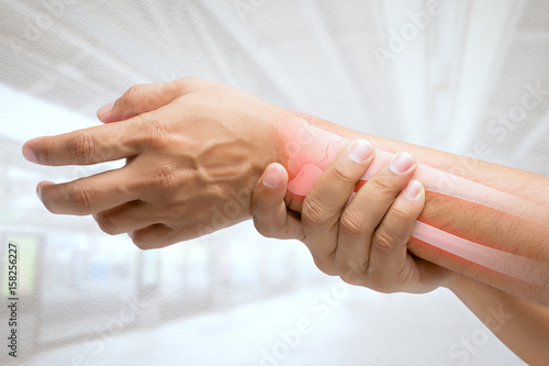 Fotomural Man massaging painful wrist on a white background. Pain concept