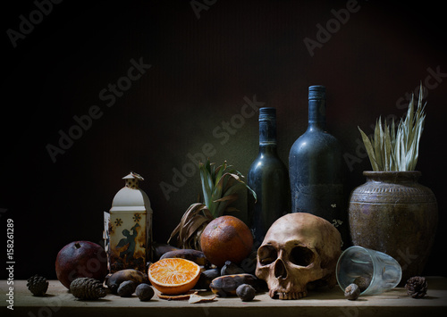 Fotografía Skull and objects expired and dried and rotten fruits on the plank in dim light night / Still life style and select focus, space for text
