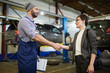 © pressmaster - Car repairman and his client handshaking in garage