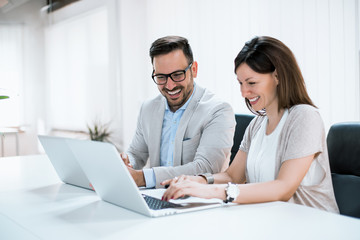 Wall Mural - Businesspeople working together in bright office, sitting at desk.