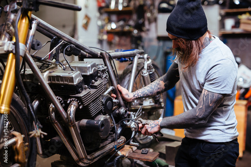 Portrait Of Focused Tattooed Man Working In Garage Customizing