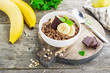 Chocolate oatmeal for breakfast with slices of a ripe banana and pieces of bitter good chocolate in a white ceramic bowl on a wooden background in a horizontal position. Example of a healthy die