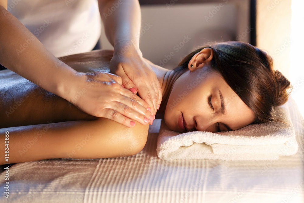 Body massage and spa treatment in modern salon with candles - obrazy, fototapety, plakaty 