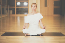 Beautiful Young Woman Sitting In Lotos Pose And Practicing Meditation In Yoga Hall