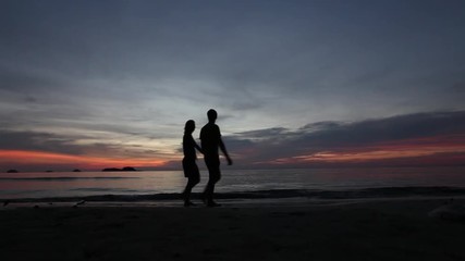 Wall Mural - couple walking together on the beach at sunset, silhouettes of man and woman, love and dating concept