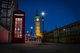 Fototapeta Big Ben - Traditional red phone booth or telephone box with the Big Ben in the background, possible the most famous English landmark, at night in London, England, UK