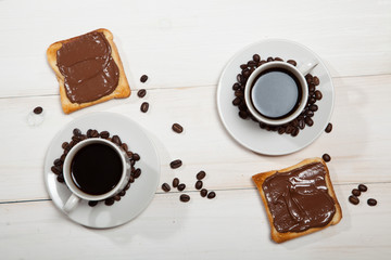 Wall Mural - Two cups of coffee and toast with chocolate on a white wooden table