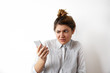 © shurkin_son - Human emotions, feelings and reactions. Attractive young woman with hair bun looking at mobile phone seeing bad news photos having scared or shocked facial expression, raising eyebrows