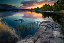Beautiful Sunset With Reflection In Water. Reeds And A Stone Beach. Karelia. Ladoga Lake.
