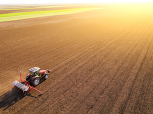 Aerial Shot Of A Farmer Seeding, Sowing Crops At Field. Sowing Is The Process Of Planting Seeds In The Ground As Part Of The Early Spring Time Agricultural Activities.