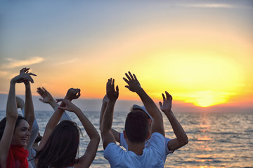 Wall Mural - group of happy young people dancing at the beach on beautiful summer sunset