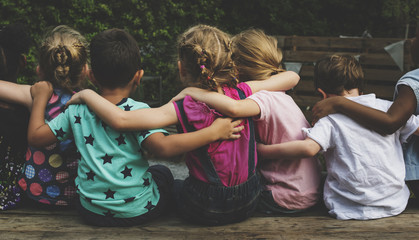 Wall Mural - Group of kindergarten kids friends arm around sitting together