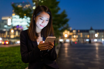 Canvas Print - Business woman sending sms on cellphone at night