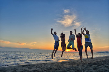 Wall Mural - Group of happy young people is running on background of sunset beach and sea