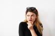© shurkin_son - Close up portrait of attractive confused woman thinking and looking aside touching her chin on white wall background. Copy space on the side. Human expressions, emotions, feelings, body language