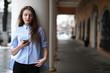 © alexkich - Young beautiful girl on a walk near building with a column