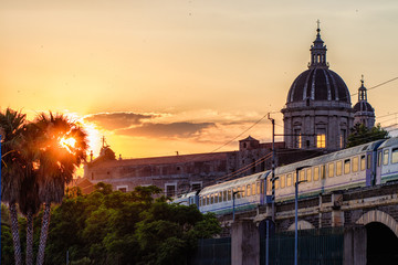 Catania, passing the train at sunset over the marina arches (archi della marina). View of the ancient walls.