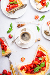 Wall Mural - Overhead shot of cups of coffee, delicious homemade strawberry cheesecake and flowers on light gray background. Top view, flat lay.