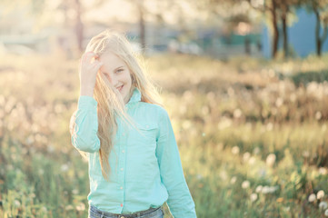 Beautiful smiling teenage girl in blouse, against green of summer park. Sunlight, happiness, fun, hair, joy.