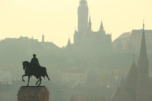 Sunset Silhouettes Of Matthias Church And Historic Buildings On Castle Hill With Equestrian Statue Of Gyula Andrassy In Kossuth Square, Budapest, Hungary, Europe