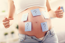 Photo Of Pregnant Woman With Question Marks On Belly