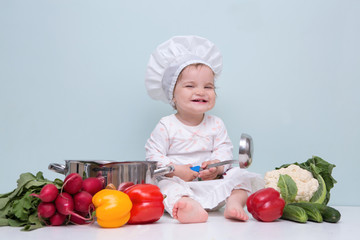 Wall Mural - Baby wearing a chef hat with vegetables and pan. .