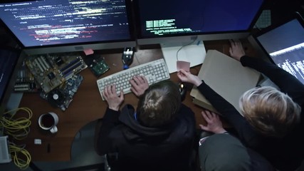 top view of three hackers working with programming code on computers in dark office