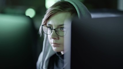 Wall Mural - closeup shot of young woman in eyeglasses sitting in front of computer and reading programming code