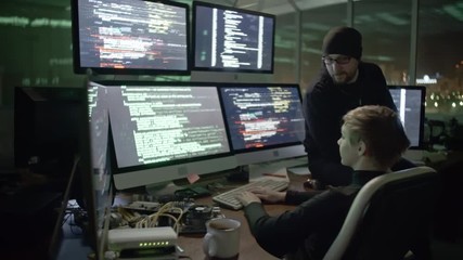 Wall Mural - young woman typing program codes on computer screens while cracking website with male colleague. man