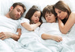 © pikselstock - Family of four lying on bed