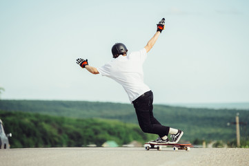 A young guy performs a complex trick on the longboard