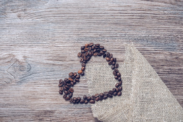 Wall Mural - Heart of coffee beans on a wooden background.