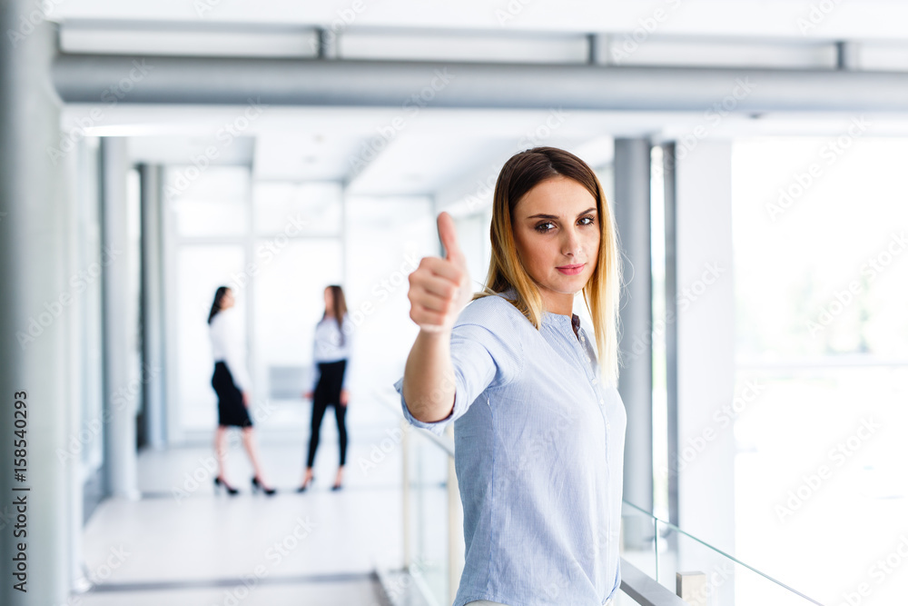 Blonde business woman standing and showing thumbs up while there are ...