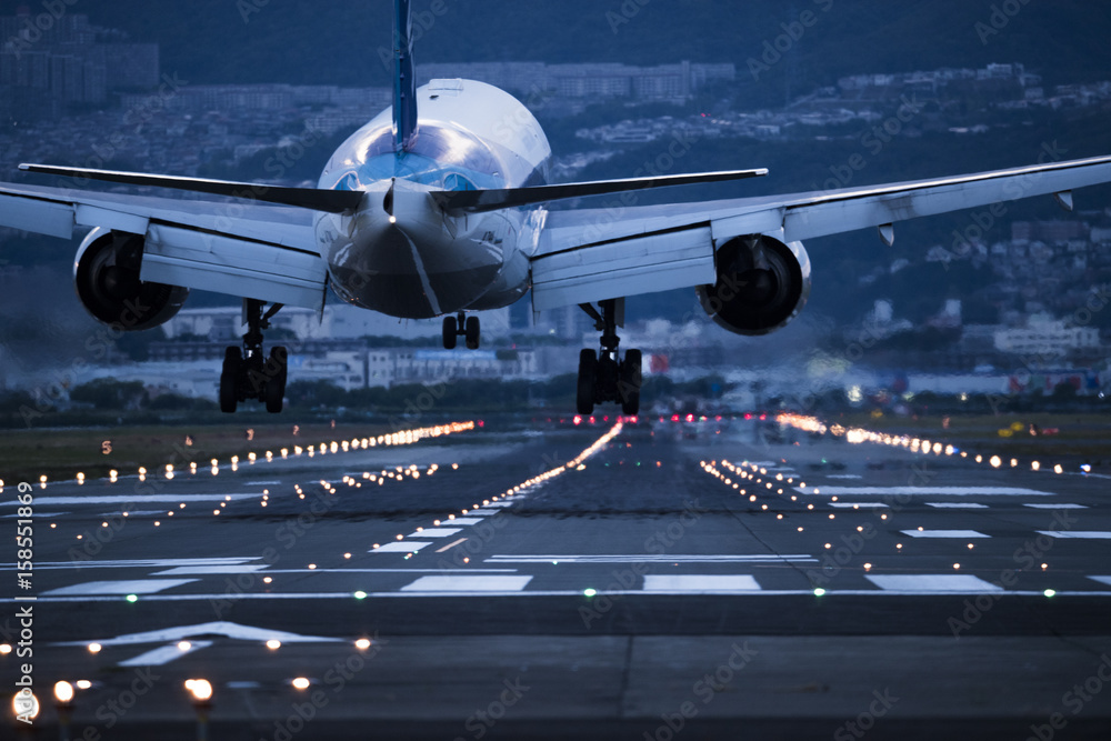 In the evening, the plane is about to land on the runway - obrazy, fototapety, plakaty 