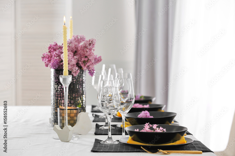 Beautiful table setting with black plates and lilac as floral decor