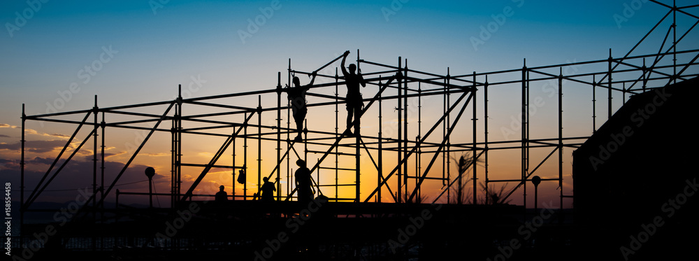 Construction workers working on scaffolding. - obrazy, fototapety, plakaty 