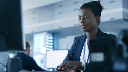 Wall Mural - african-american female scientist working on a computer with her colleagues at research center. her 