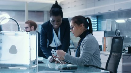 Wall Mural - black and caucasian female scientists working on a computer, correlating their notes and experience.