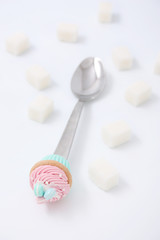 
Spoon with cakes and sugar cubes on a white background